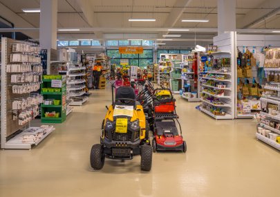 Zahradní traktor a sekačky vystavené v uličce prodejny